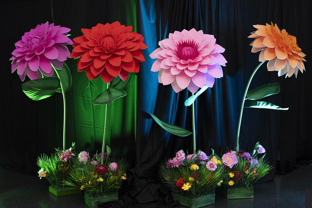 Four oversized flower sculptures in sunset hues decorate the scene at Party Arty: Painted Night.