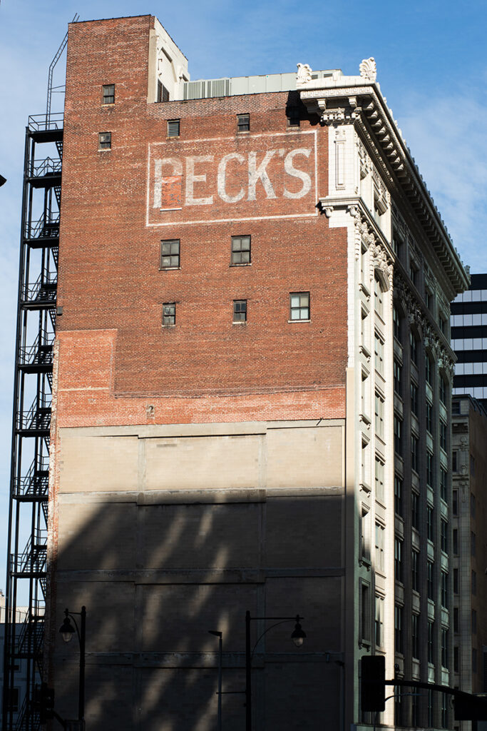 Peck’s Department Store 1044 Main St. “The operation that became Peck’s Department Store in 1914 opened as Doggett and Orrison in 1868,” according to We Were Hanging by a Thread. The dry goods store, which sold clothing and textiles, would later evolve into Peck’s and play a vital role in one of the city’s greatest entrepreneurial stories. “Nell [Donnelly] started in her basement and got an order for 16 dresses from Peck’s department store in 1916,” according to Jackson and Brownfield. “Reportedly, she delivered the dresses, and they sold out in three days. Then, they gave her an order for 300 dresses.” Peck’s orders effectively launched her business, which grew into the Donnelly Garment Company and its iconic Nelly Don dress line: women’s clothing that finally ditched the shapeless, potato-sack style for something wearable and attractive. In February, the Kansas City Business Journal reported that the former Peck’s Department Store building is the subject of a proposal to convert the ground level into a restaurant and commercial space, with 74 loft apartments planned on the remaining floors.
